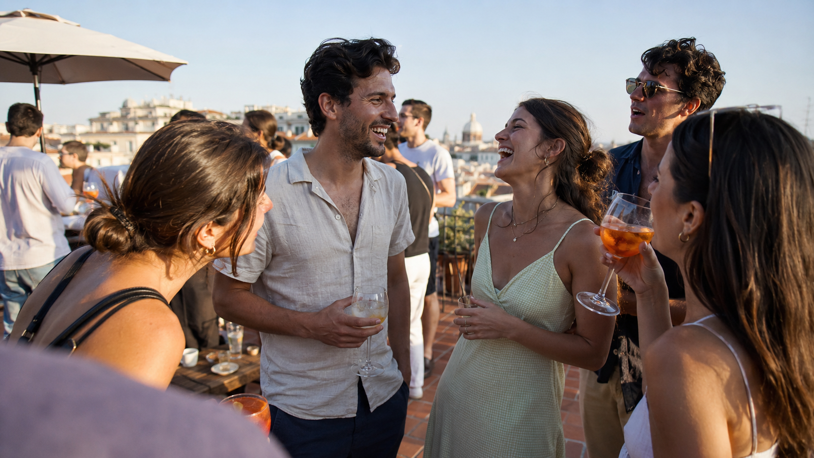 Casual rooftop gathering in a Mediterranean city — a relaxed man mid-laugh in an open group conversation with three attractive women and another guy