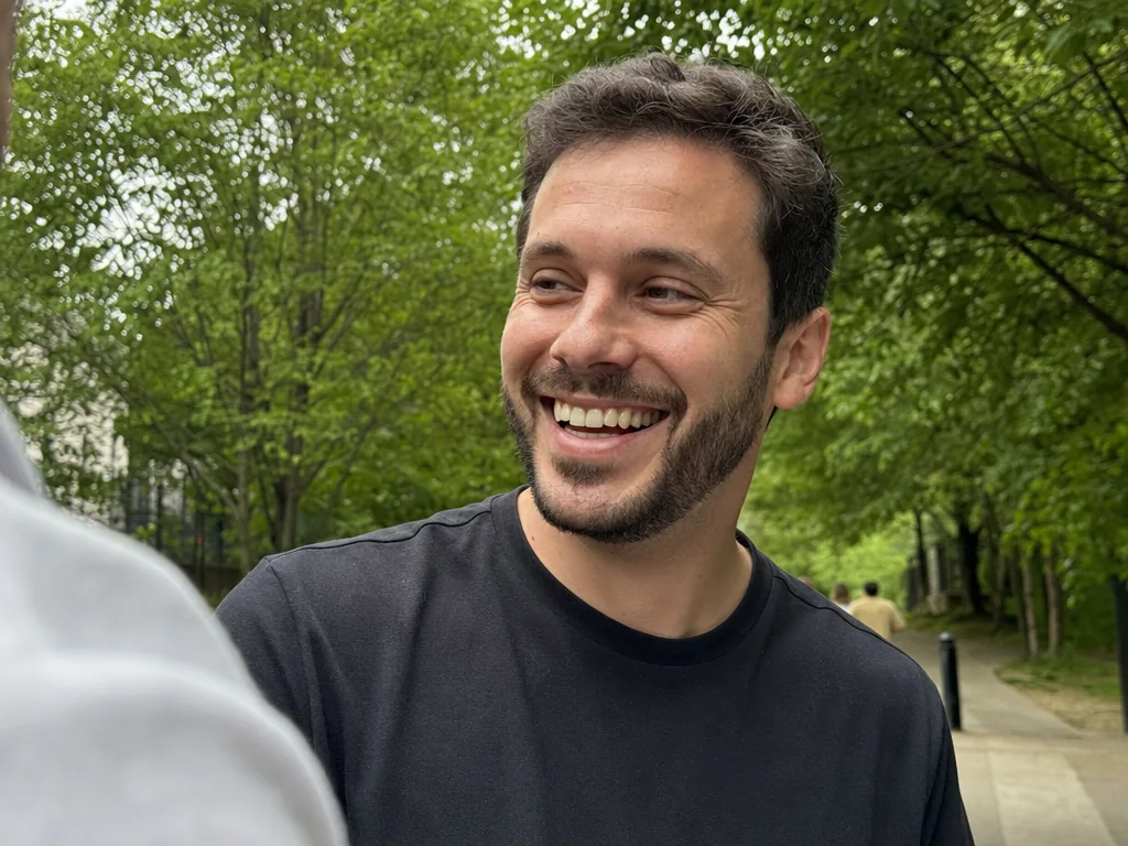 Well-groomed man laughing naturally outdoors, looking slightly off camera